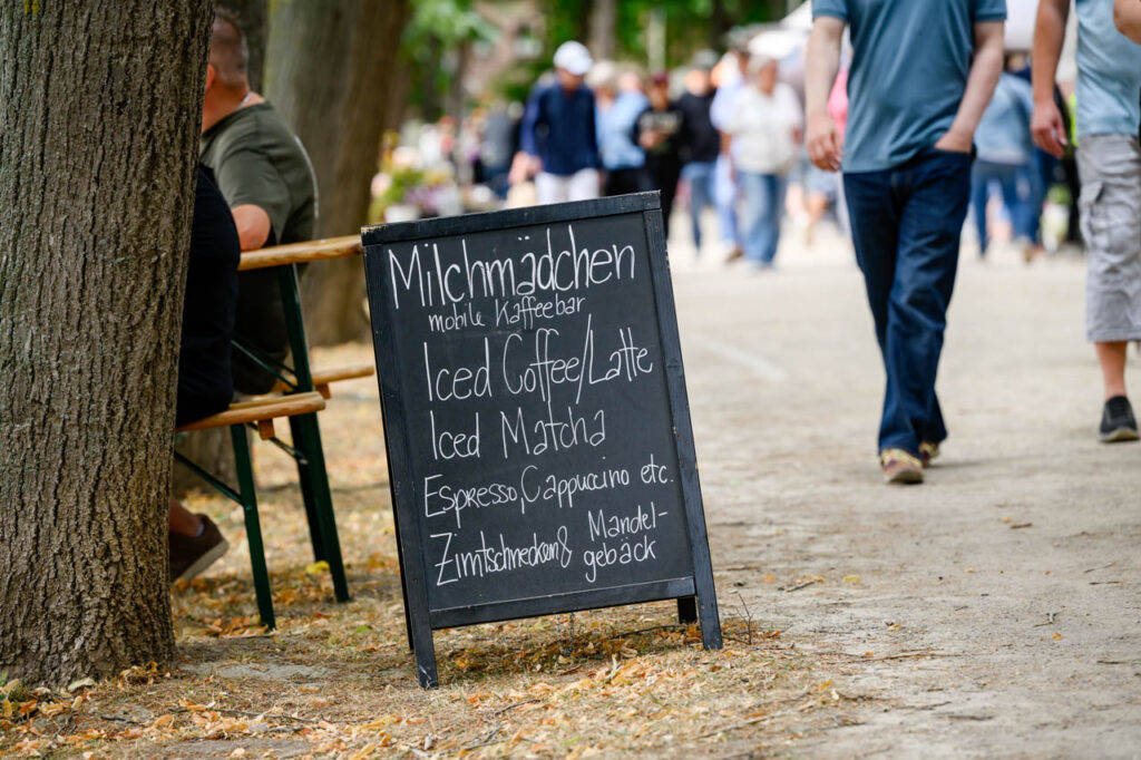 Hinweisschild einer mobilen Kaffeebar am Weg zwischen den Marktständen beim Fest am See 2026.