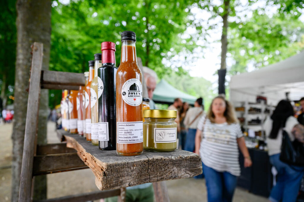 Flaschen mit Saucen und weitere Produkte an einem Marktstand beim Fest am See 2026.
