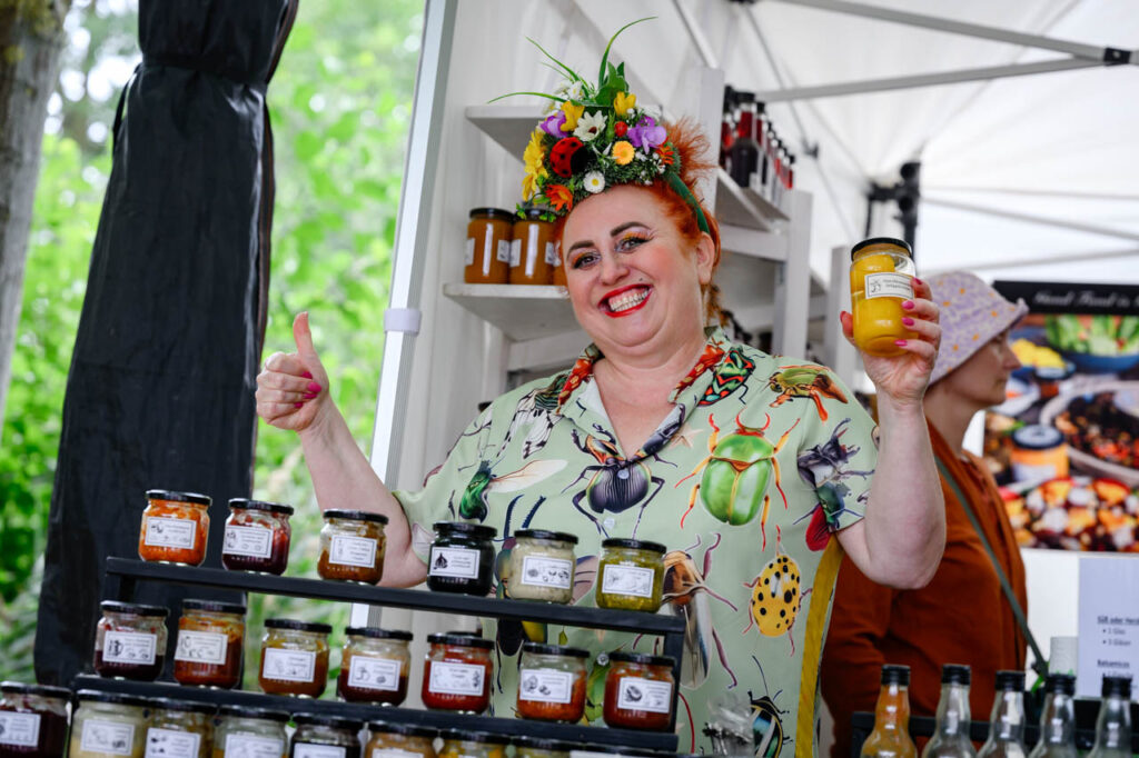 Ausstellerin präsentiert verschiedene Produkte an ihrem Marktstand beim Fest am See 2026.