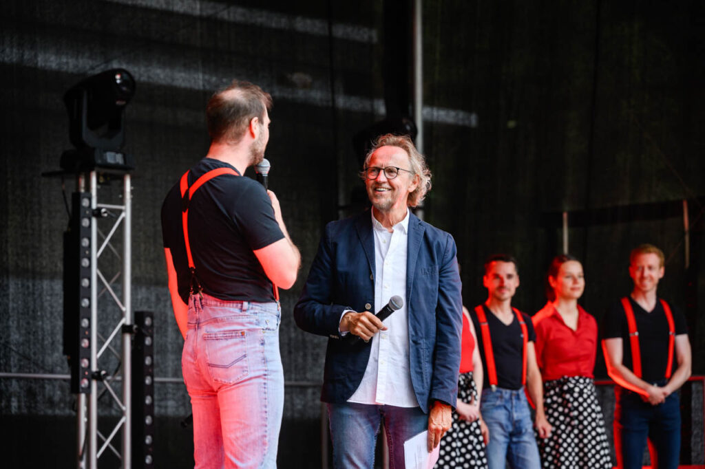 Moderator im Gespräch mit einem Tänzer auf der Bühne beim Fest am See 2026.