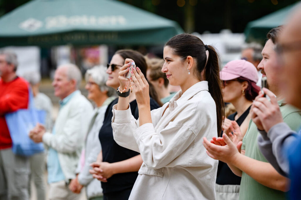 Besucherin fotografiert das Bühnenprogramm beim Fest am See 2026 mit ihrem Smartphone.