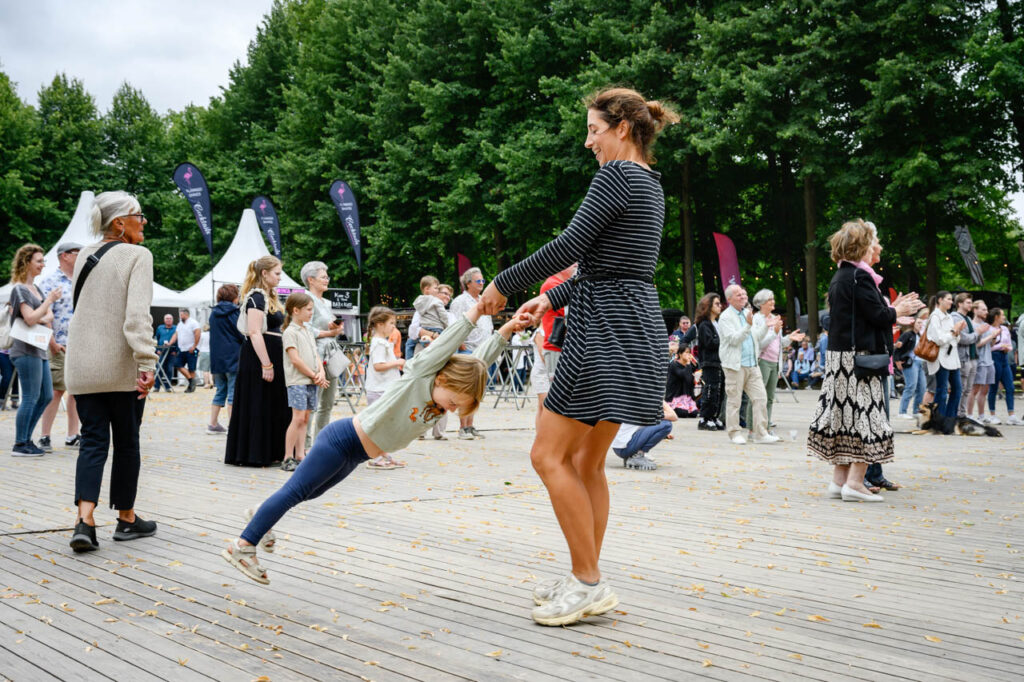 Eine Erwachsene tanzt mit einem Kind vor der Bühne beim Fest am See 2026 im Schlosspark Wickrath.