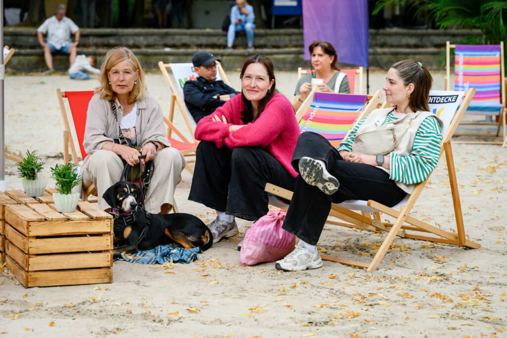 Besucherinnen entspannen gemeinsam mit einem Hund in Liegestühlen beim Fest am See im Schlosspark Wickrath.