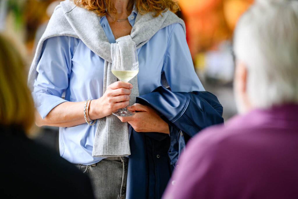 Besucherin mit einem Glas Weißwein beim Fest am See 2026 im Schlosspark Wickrath.