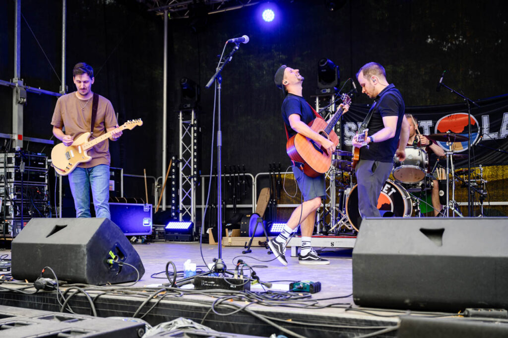 Band spielt mit Gitarren und Schlagzeug live auf der Bühne beim Fest am See 2026.