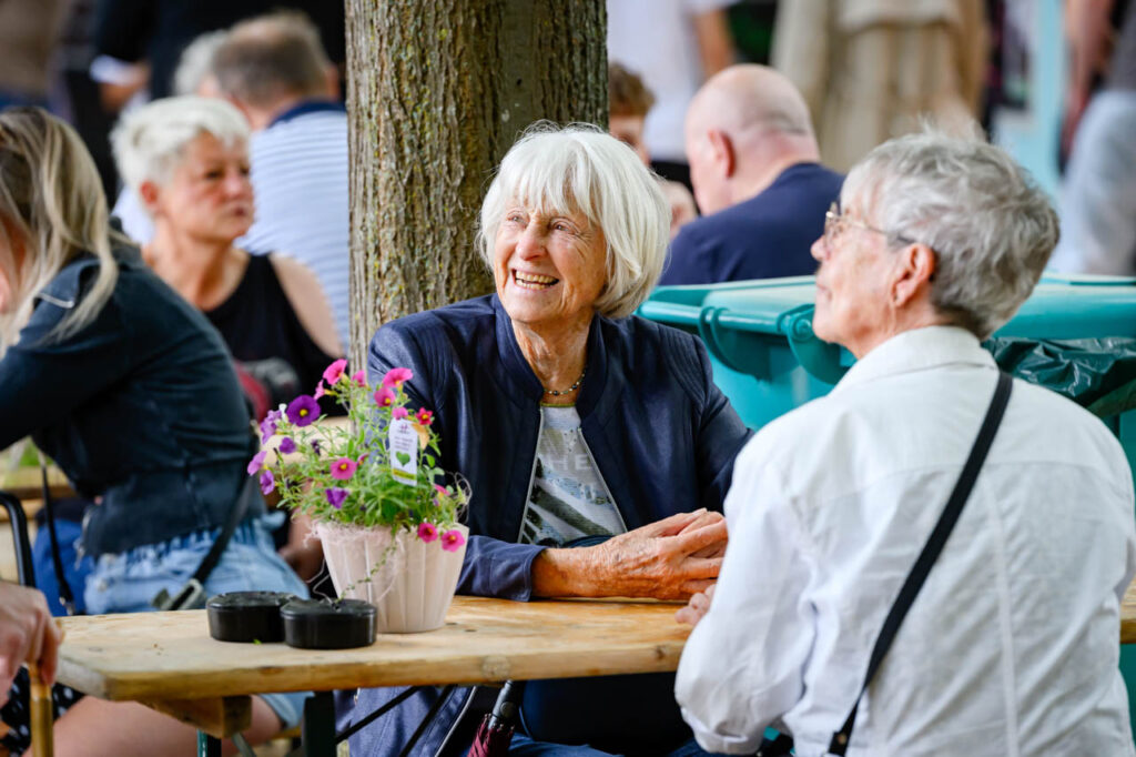 Zwei ältere Besucherinnen sitzen gemeinsam an einem Tisch beim Fest am See im Schlosspark Wickrath.